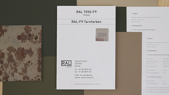RAL F9 Farbregisterkarte. Das Bild zeigt das verbindliche Farbmuster zu den Bundeswehrtarnfarben. Exemplarisch liegt die Farbe "Tarngrau" mittig, zugefaltet. Im Hintergrund sind weitere Tarnfarben zu sehen. | RAL FARBEN

RAL F9 colour primary standard card. The picture shows the binding colour samples for the Bundeswehr camouflage colours. As an example, the colour “camouflage grey” is in the middle, folded. More camouflage colours can be seen in the background. | RAL COLOURS