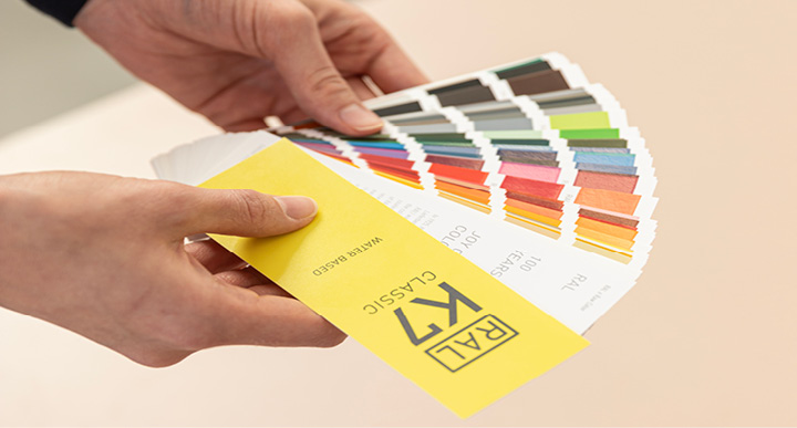 RAL K7 Farbfächer | RAL FARBENJubiläumsdesign von Raw Color .Der Farbfächer wird in Händen gehalten und aufgefächert.RAL K7 Colour fan | RAL COLOURSAnniversary design by Raw Colour .The colour fan is held in hands and fanned out.