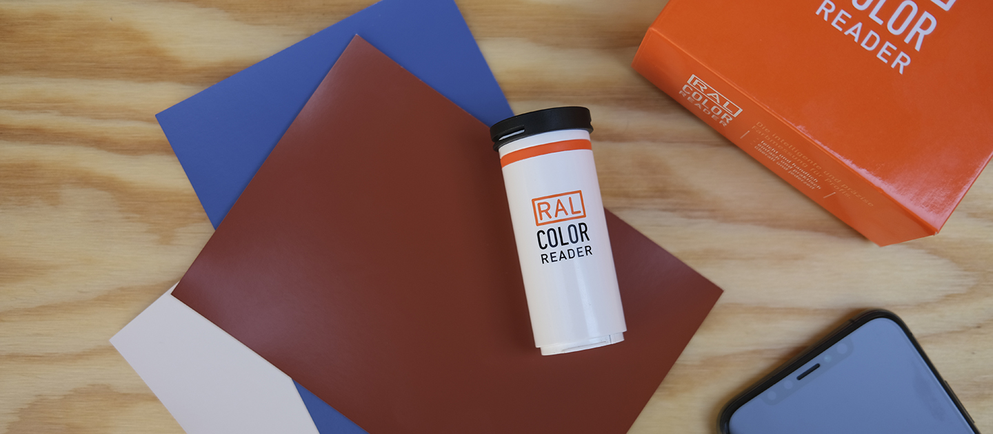 RAL COLOR READER | RAL FARBEN
Das Bild zeigt das digitale Farbmessgerät RAL COLOR READER aus der Vogelperspektive. Das Gerät liegt auf mehreren RAL Farbmustern in braun, blau und grau. Am Rand sind ein Smartphone sowie die Verpackung zu sehen.

RAL COLOR READER | RAL COLOURS
The picture shows the digital colour measuring device RAL COLOR READER from a bird's eye view. The device is based on several RAL colour samples in brown, blue and grey. A smartphone and the packaging can be seen on the edge.